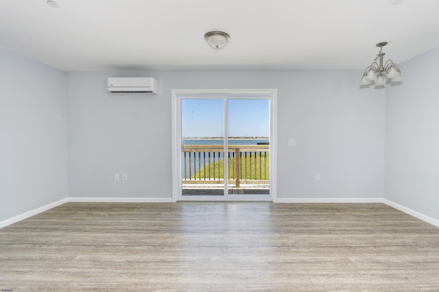 unfurnished room with a wall unit AC, light hardwood / wood-style flooring, a water view, and a chandelier