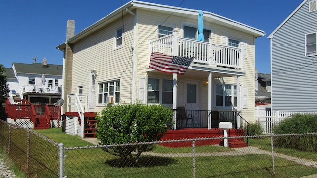 view of front of home with a balcony and a front lawn