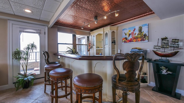 bar featuring light tile patterned flooring and white cabinetry