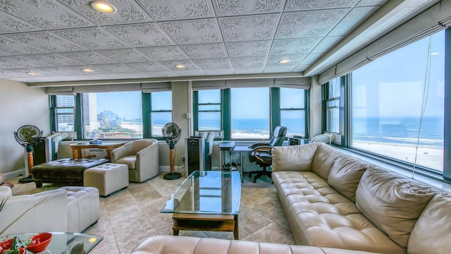 living room with light tile patterned flooring, a water view, and a wealth of natural light