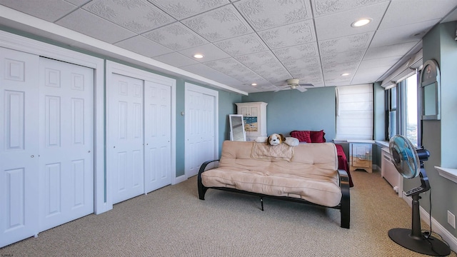 bedroom featuring a drop ceiling, carpet, and two closets