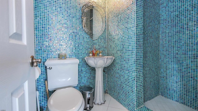 bathroom with toilet, tile patterned floors, and tile walls