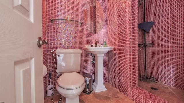 bathroom with tile patterned floors, tile walls, a tile shower, and toilet