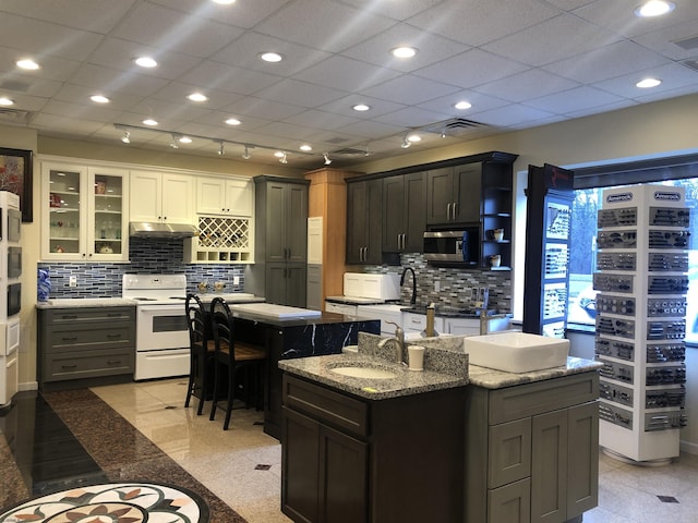 kitchen with a center island with sink, white electric stove, a breakfast bar area, white cabinetry, and sink