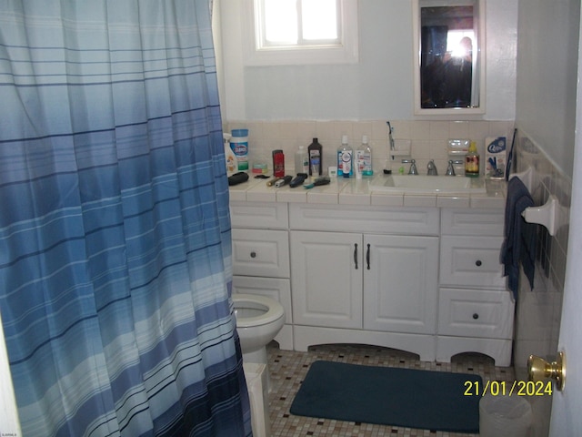 bathroom with vanity, tasteful backsplash, toilet, and tile patterned flooring