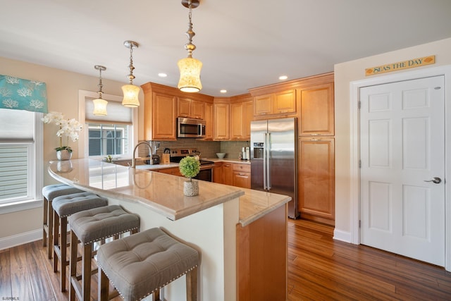 kitchen with pendant lighting, a kitchen breakfast bar, stainless steel appliances, decorative backsplash, and kitchen peninsula