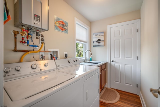 clothes washing area featuring sink, washing machine and dryer, dark hardwood / wood-style floors, cabinets, and tankless water heater