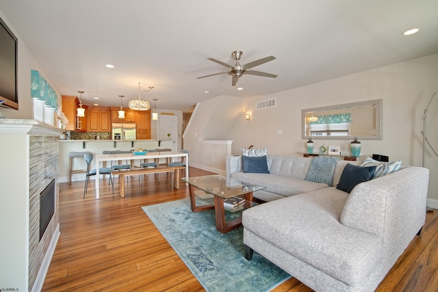 living room featuring a fireplace, light hardwood / wood-style floors, and ceiling fan