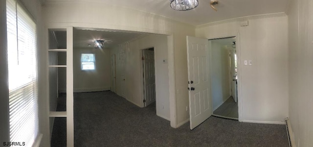 hall with ornamental molding and dark carpet