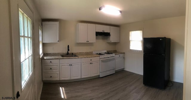 kitchen featuring black fridge, sink, white gas stove, and white cabinets