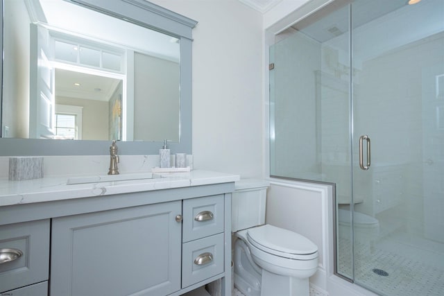 bathroom featuring toilet, vanity, a shower with door, and crown molding