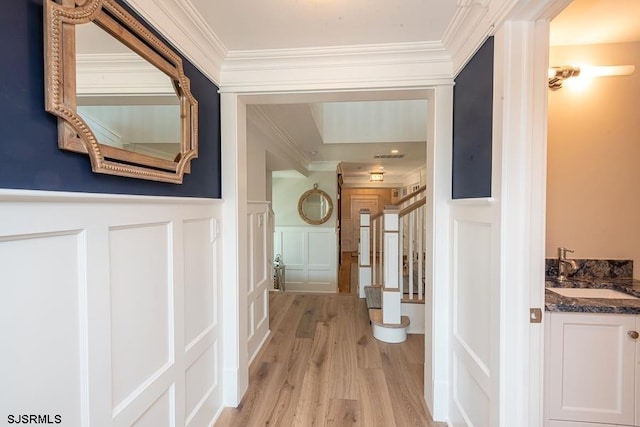 hall with sink, crown molding, and light hardwood / wood-style flooring