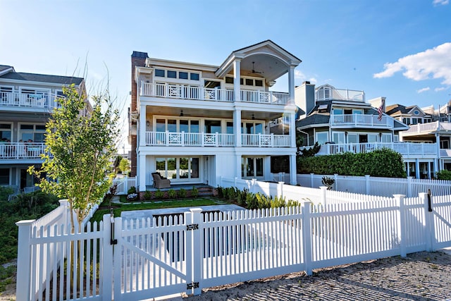 rear view of property featuring a balcony, ceiling fan, and covered porch