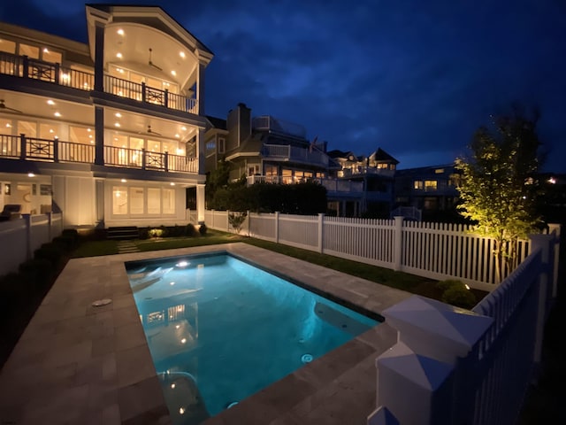 pool at twilight with ceiling fan and a patio area