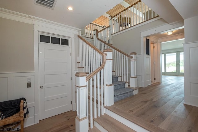 stairs featuring hardwood / wood-style floors and crown molding