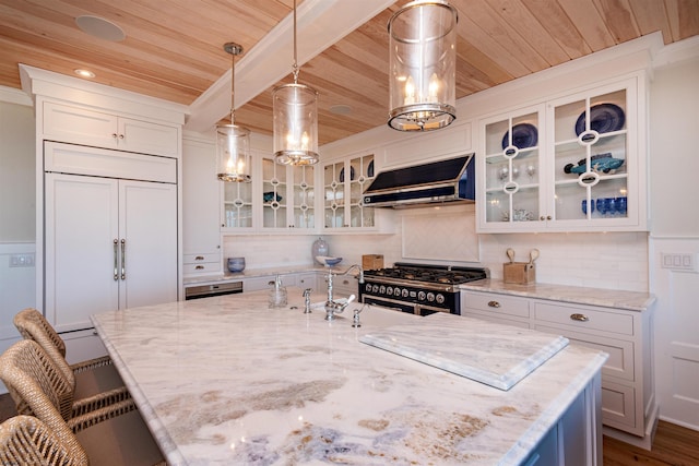 kitchen with ventilation hood, light stone countertops, high end appliances, pendant lighting, and white cabinets