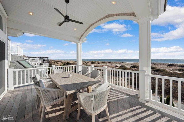 wooden deck featuring ceiling fan, a water view, and a view of the beach