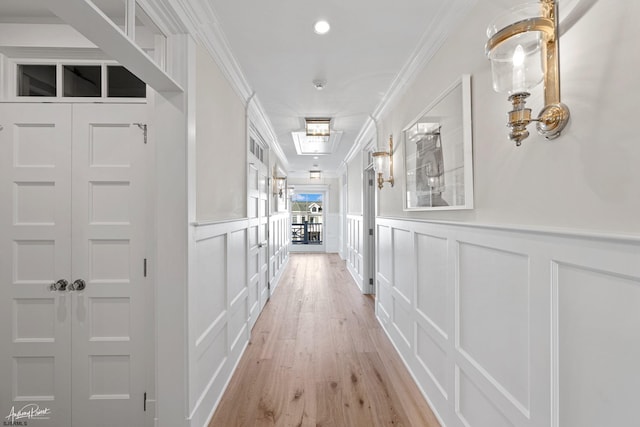 hall with light hardwood / wood-style floors and crown molding