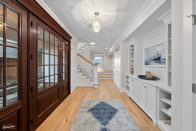 entrance foyer with light wood-type flooring, a wealth of natural light, and ornamental molding