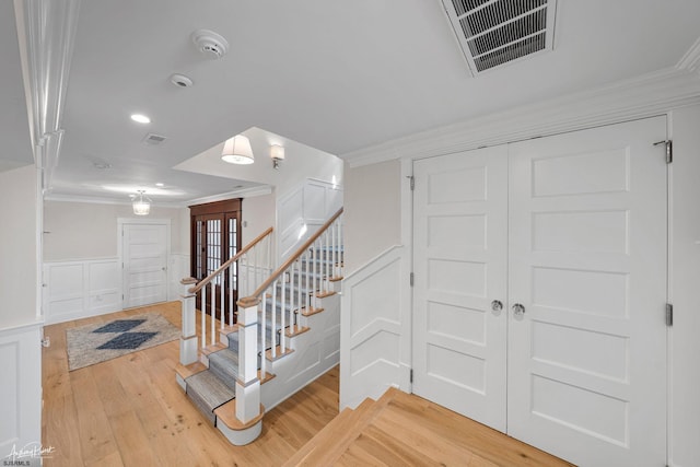 stairs with wood-type flooring and ornamental molding