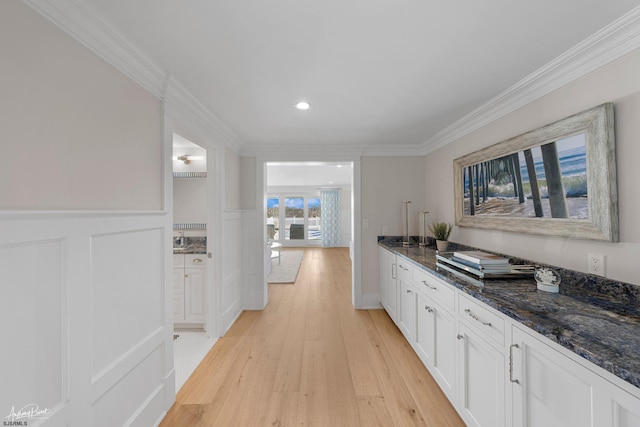 kitchen featuring white cabinets, light hardwood / wood-style flooring, crown molding, and dark stone counters