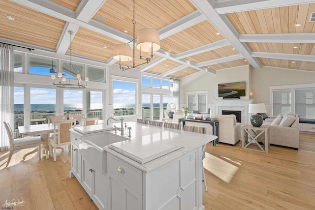 kitchen with hanging light fixtures, sink, white cabinetry, and a center island with sink