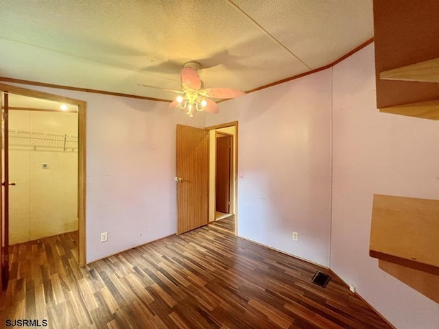 empty room with dark wood-type flooring, ceiling fan, and a textured ceiling