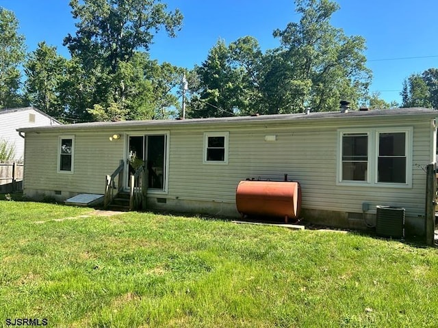 rear view of house featuring cooling unit and a lawn