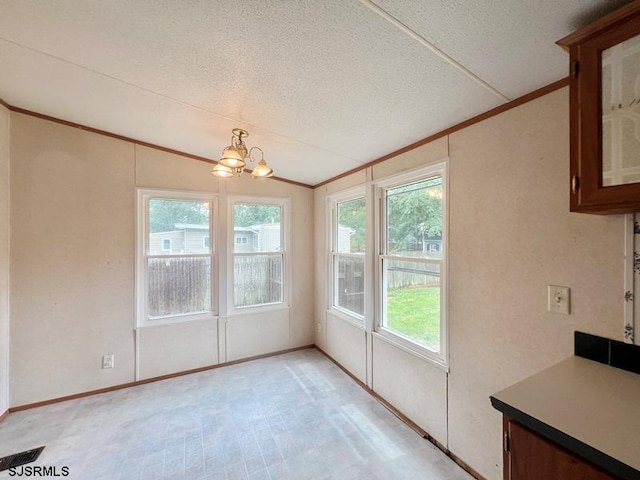 unfurnished dining area featuring lofted ceiling, plenty of natural light, a chandelier, and a textured ceiling