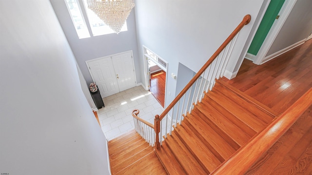 stairs with an inviting chandelier, hardwood / wood-style flooring, and a high ceiling