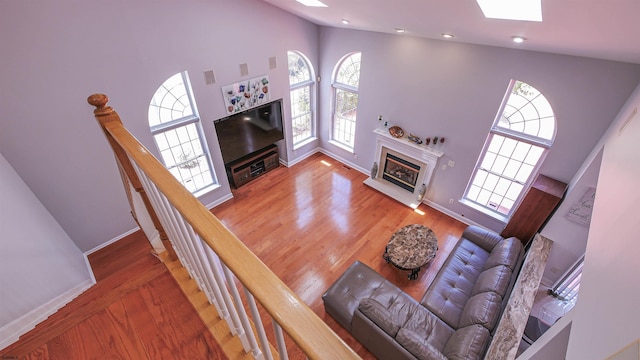 living room with hardwood / wood-style floors, a skylight, and high vaulted ceiling