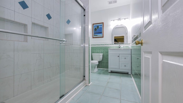 bathroom featuring tile walls, vanity, walk in shower, toilet, and tile patterned floors