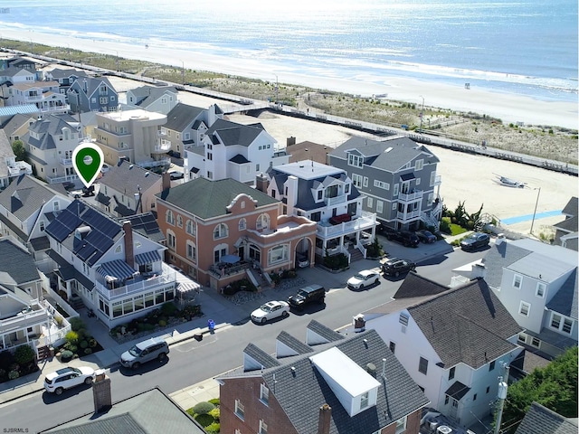 drone / aerial view featuring a water view, a residential view, and a view of the beach