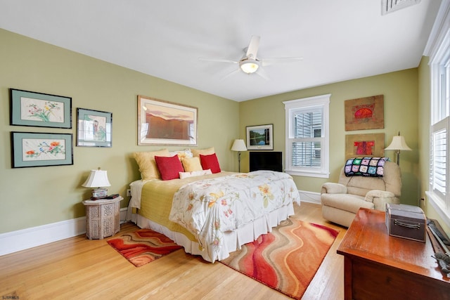 bedroom featuring multiple windows, baseboards, and wood finished floors