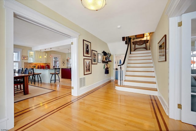 foyer featuring stairs, visible vents, baseboards, and wood finished floors