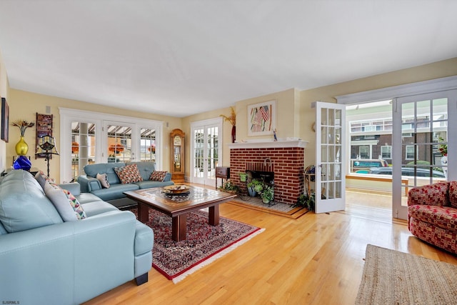 living area featuring french doors, a brick fireplace, and wood finished floors