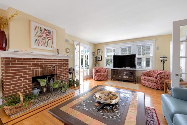 living room with french doors, a fireplace, and wood finished floors