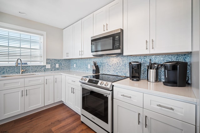 kitchen featuring stainless steel appliances, sink, decorative backsplash, white cabinetry, and dark wood-type flooring