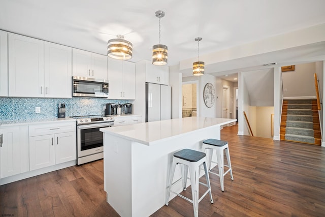 kitchen featuring white fridge, electric stove, hanging light fixtures, dark hardwood / wood-style flooring, and white cabinets