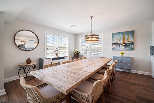 dining room with dark wood-type flooring and an inviting chandelier