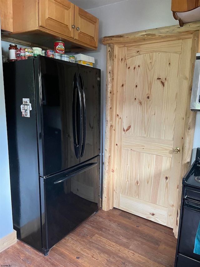 kitchen featuring electric range, hardwood / wood-style floors, and black refrigerator