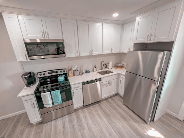 kitchen featuring stainless steel appliances, sink, light wood-type flooring, white cabinets, and tasteful backsplash