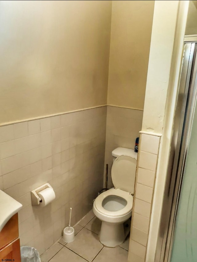 bathroom featuring vanity, tile patterned floors, toilet, and tile walls