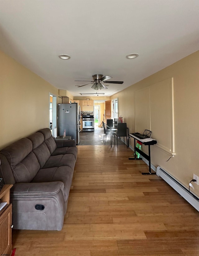 living room with ceiling fan, light hardwood / wood-style floors, and a baseboard heating unit