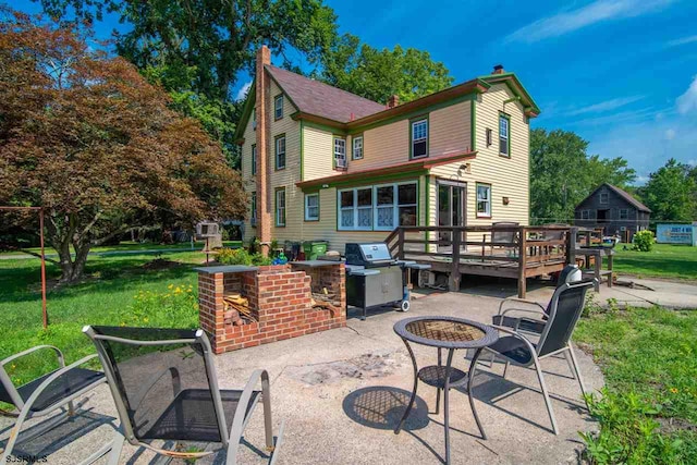 rear view of house with a deck, a patio, and a lawn