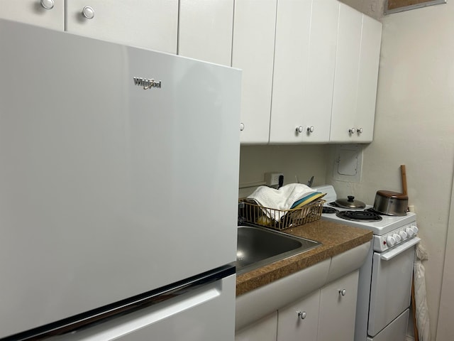 kitchen with white cabinetry, sink, white range with electric stovetop, and stainless steel refrigerator