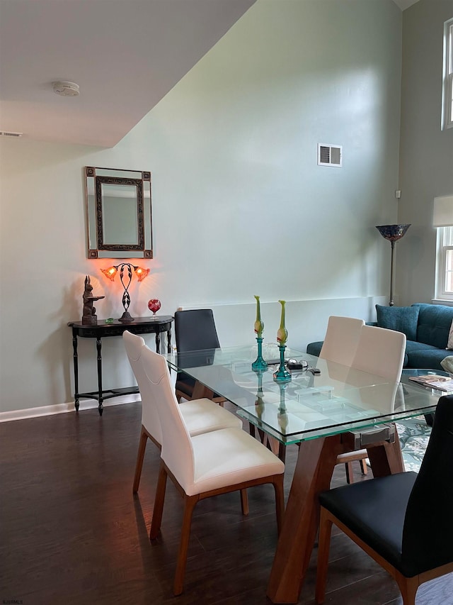 dining room with dark wood-type flooring and high vaulted ceiling