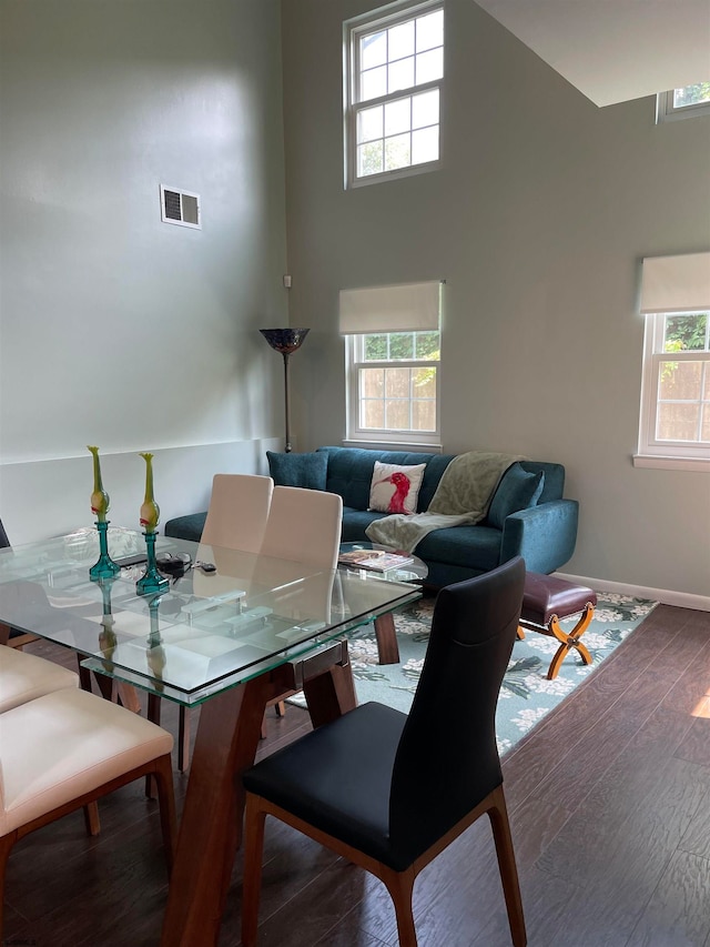 dining space featuring a high ceiling and hardwood / wood-style floors