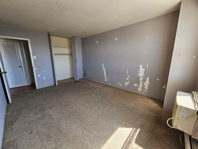 unfurnished bedroom with a closet and dark colored carpet