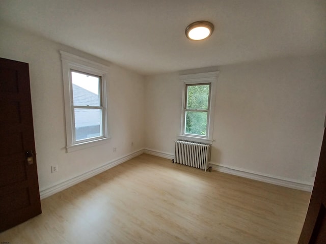 empty room featuring light wood-type flooring and radiator